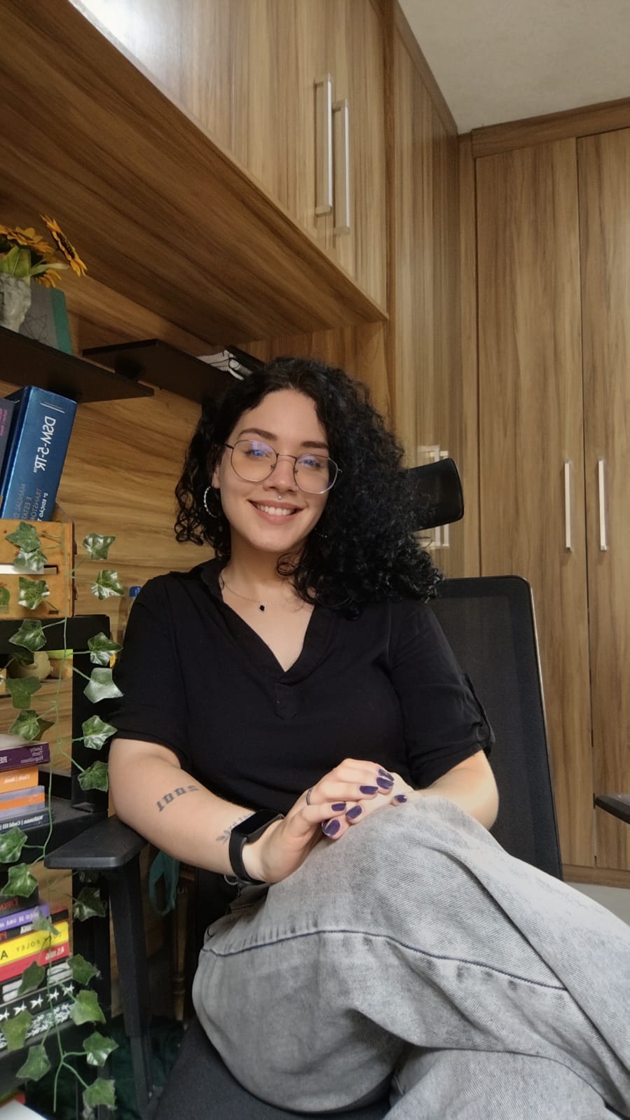 Clarissa Di Cola, psicóloga em Juiz de Fora, sorrindo em seu espaço de atendimento